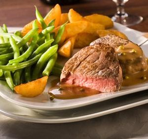 medium rare fried beef fillet in pepper sauce, with potato wedges and green beans