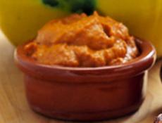 closeup of a plate of barbecued calcots, catalan sweet onions, and a bowl with romesco sauce